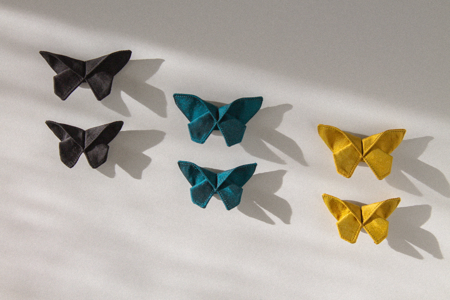 Three of the six colors of the small Origami Silk Butterfly Hair Clips on white background.