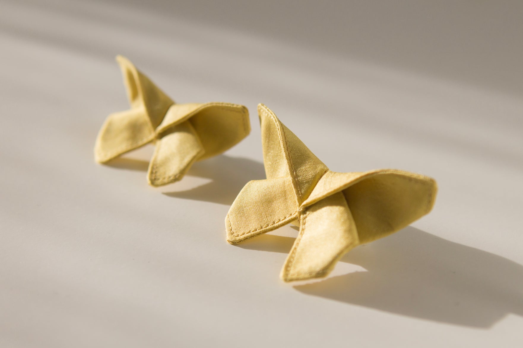 Origami Silk Butterfly Hair Clips in Butter Yellow on white background.