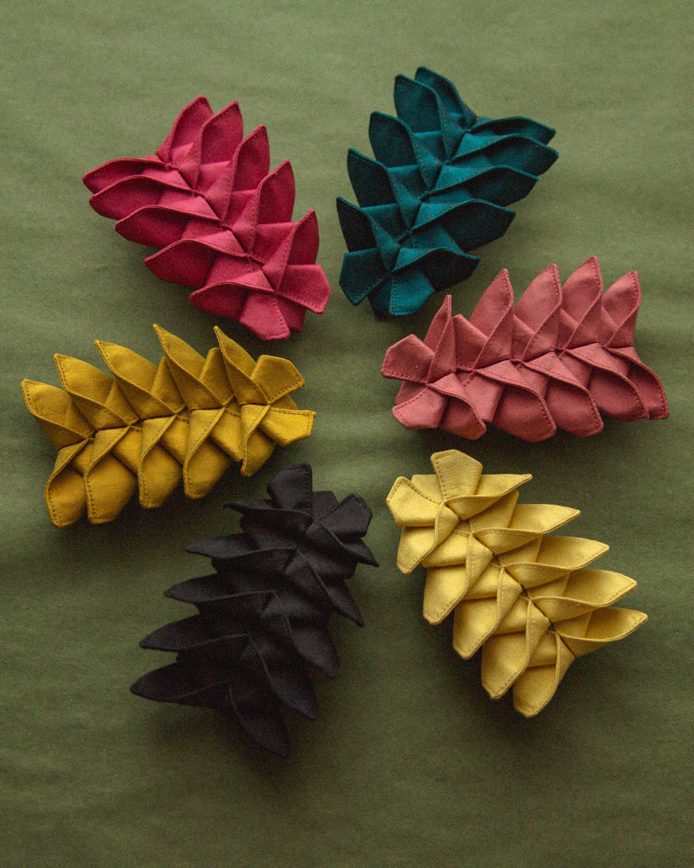 All the different colors of the Origami Silk Butterfly Barrette Hair Clip on green background.